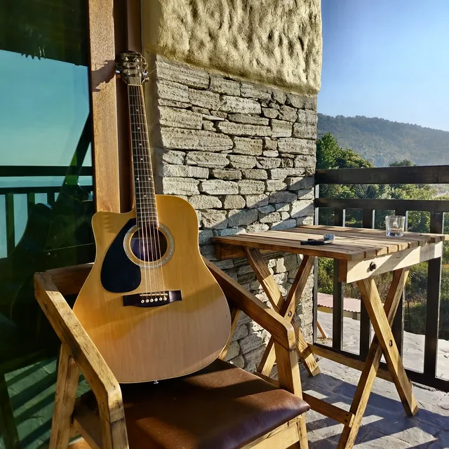 A left-handed acoustic guitar resting on a wooden chair on a balcony